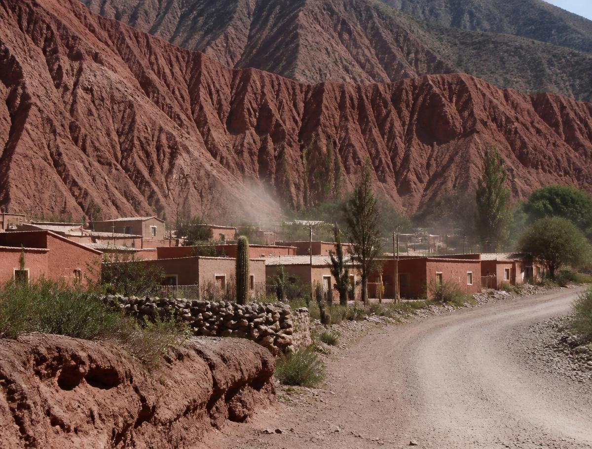 Adobe colonial buildings below red rock cliffs in Salta province, Argentina