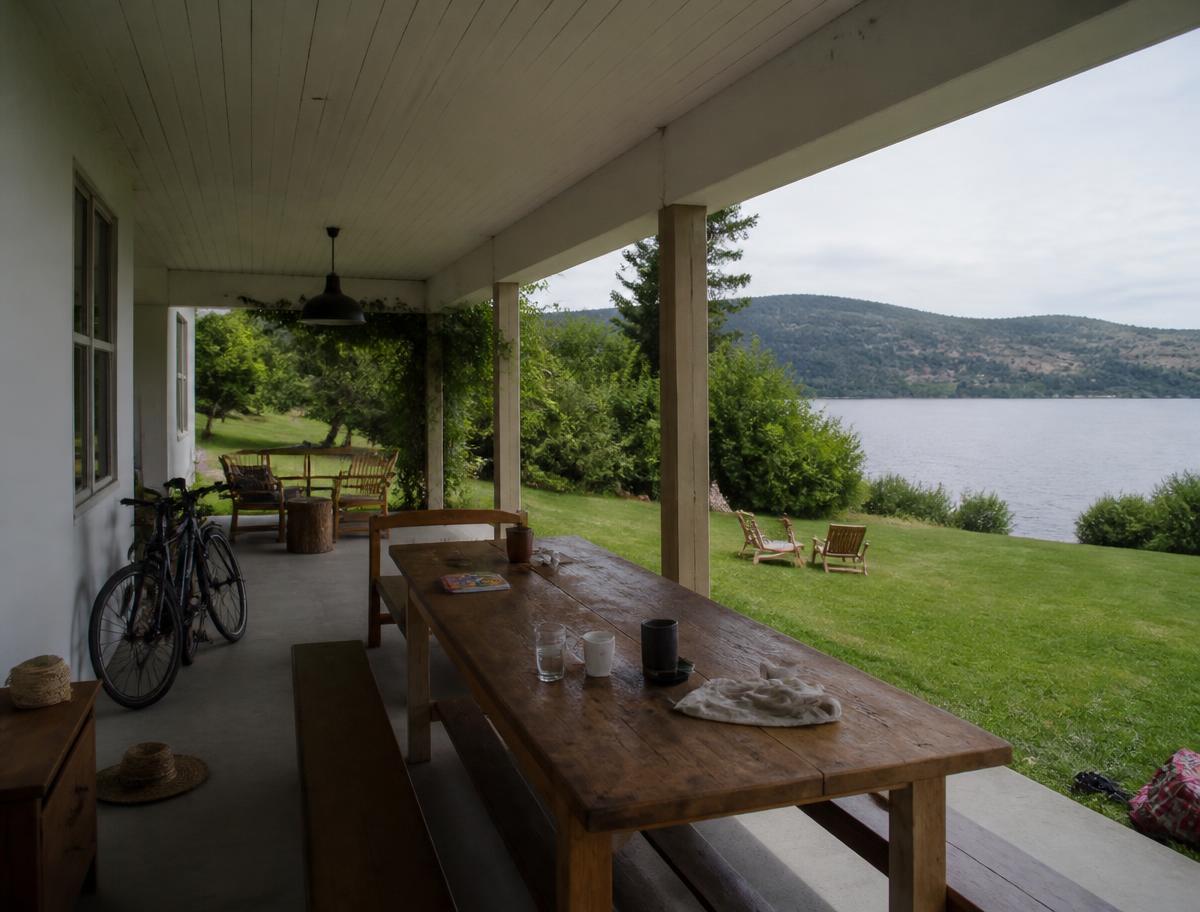 Family holiday house with a wide covered porch, long dining table and lawn beside an Argentine lake
